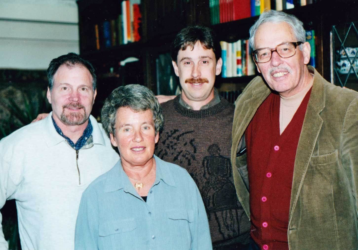 A group of people posing for a picture in front of a bookshelf