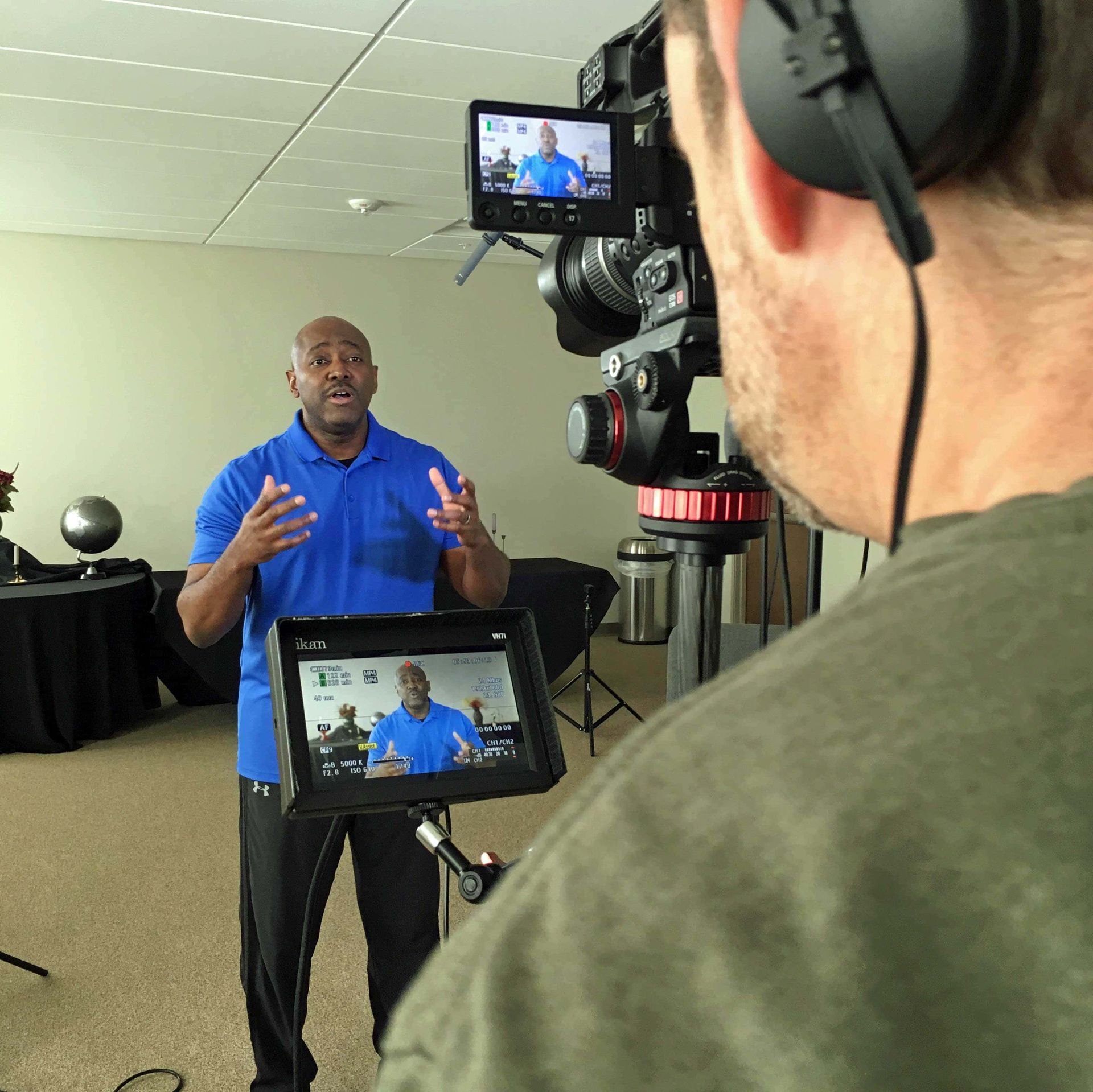 A man in a blue shirt is being filmed by a camera