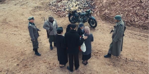A group of people are standing in a circle in front of a motorcycle.
