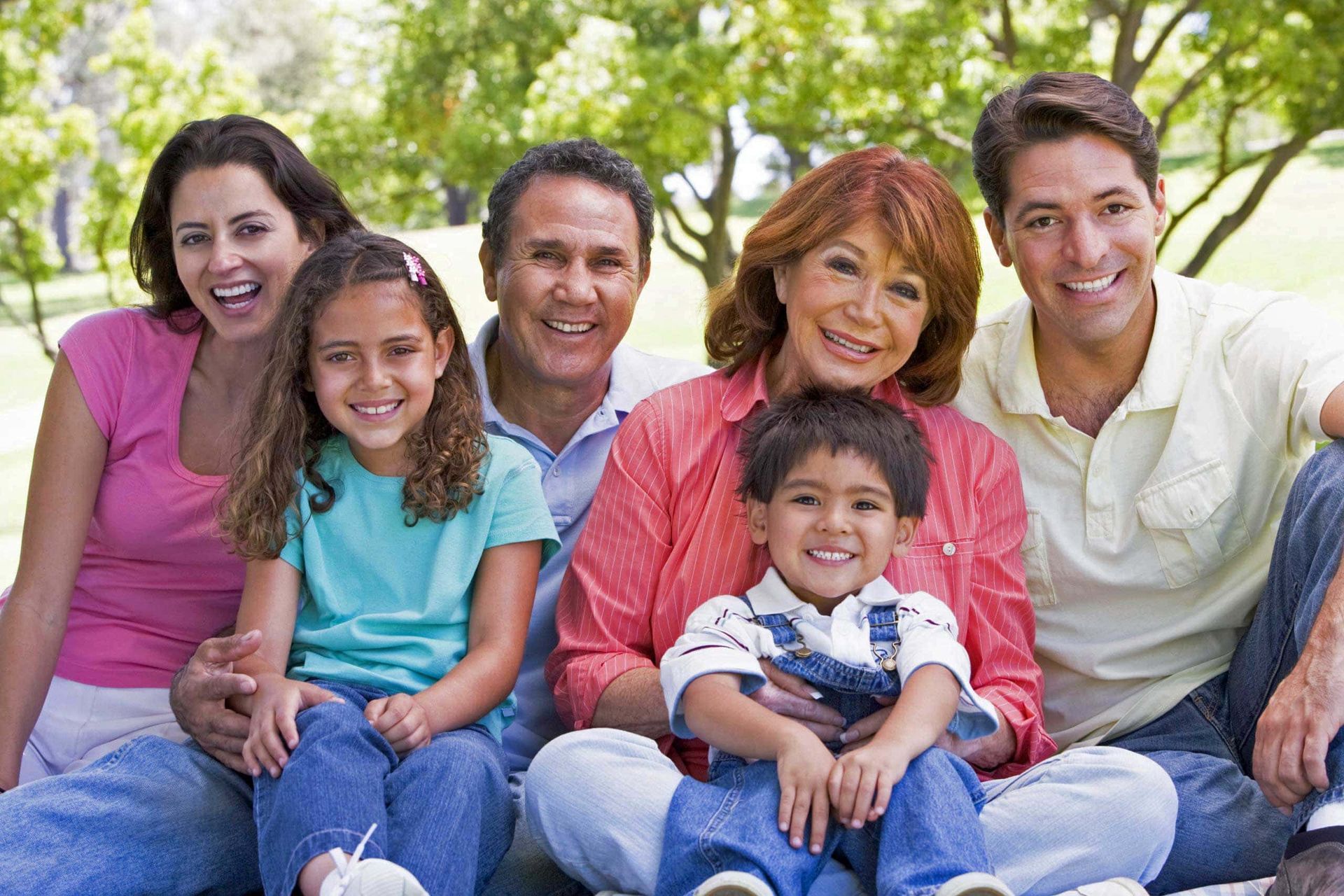 A large family is posing for a picture in a park.