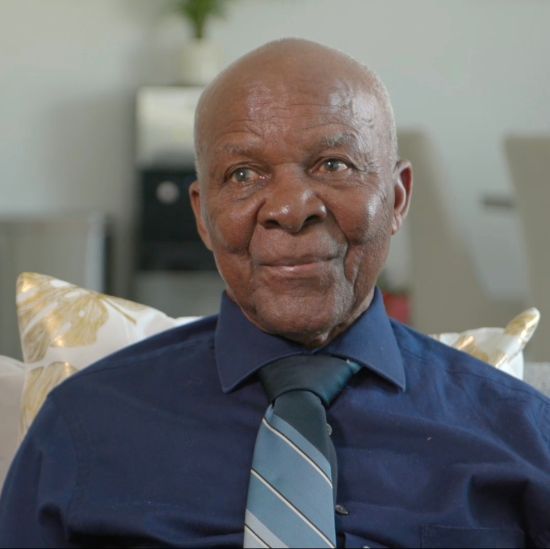 A man in a blue shirt and tie is smiling