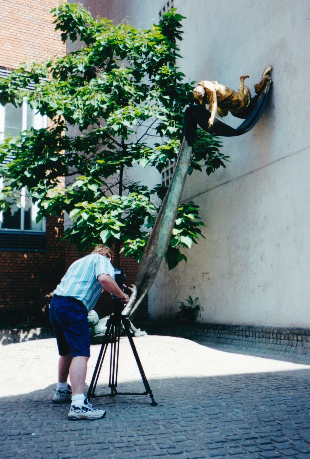A man taking a picture of a statue on a tripod