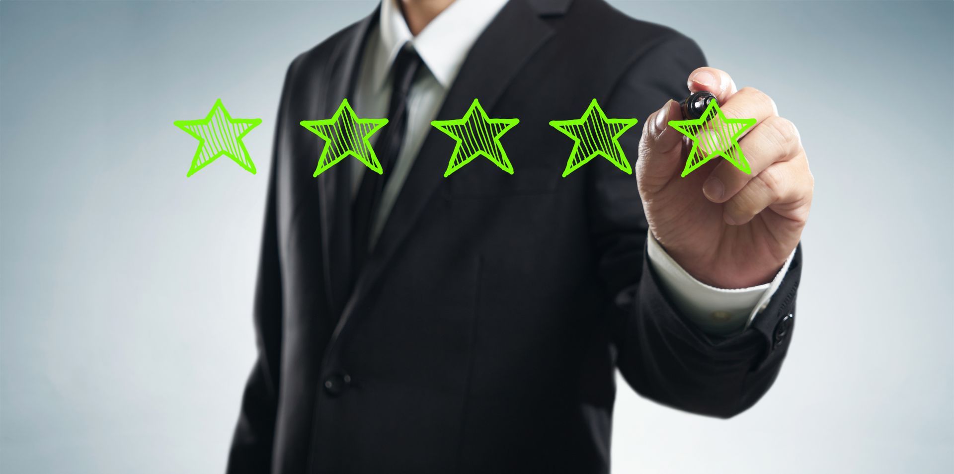 A man in a suit is drawing five stars with a marker