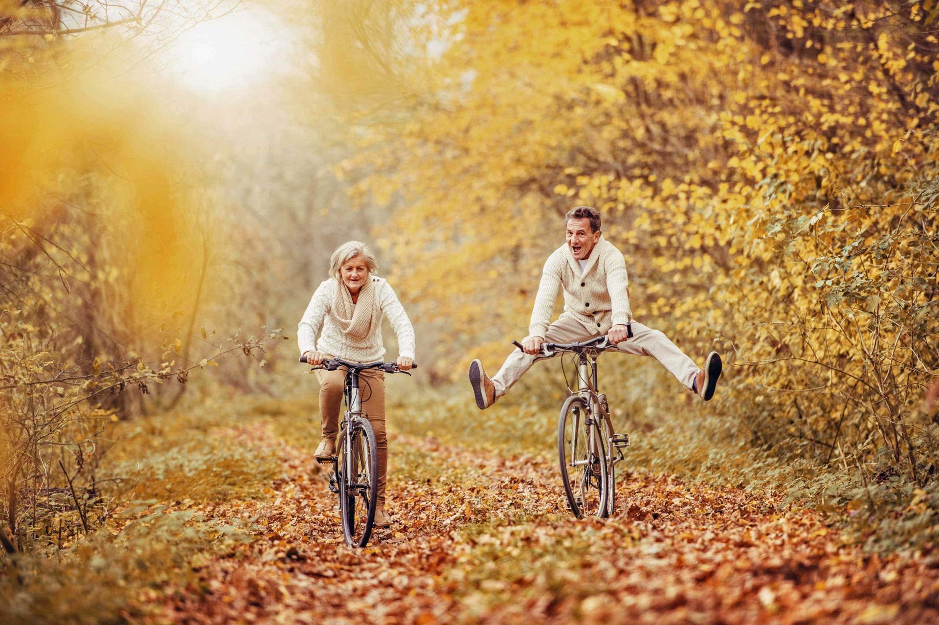 A man and a woman are riding bicycles in the woods.