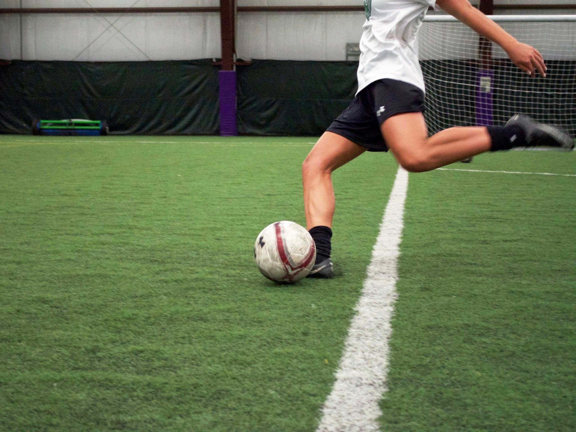 A person is kicking a soccer ball on a field.