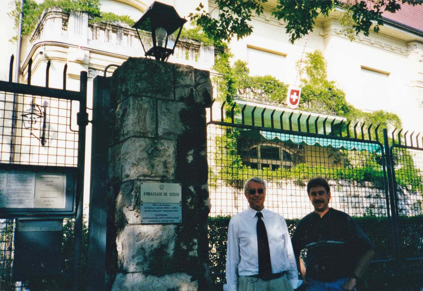 Two men standing in front of a building with the letter c on it
