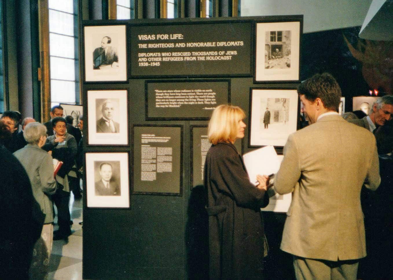 A woman stands in front of a wall that says visas for life