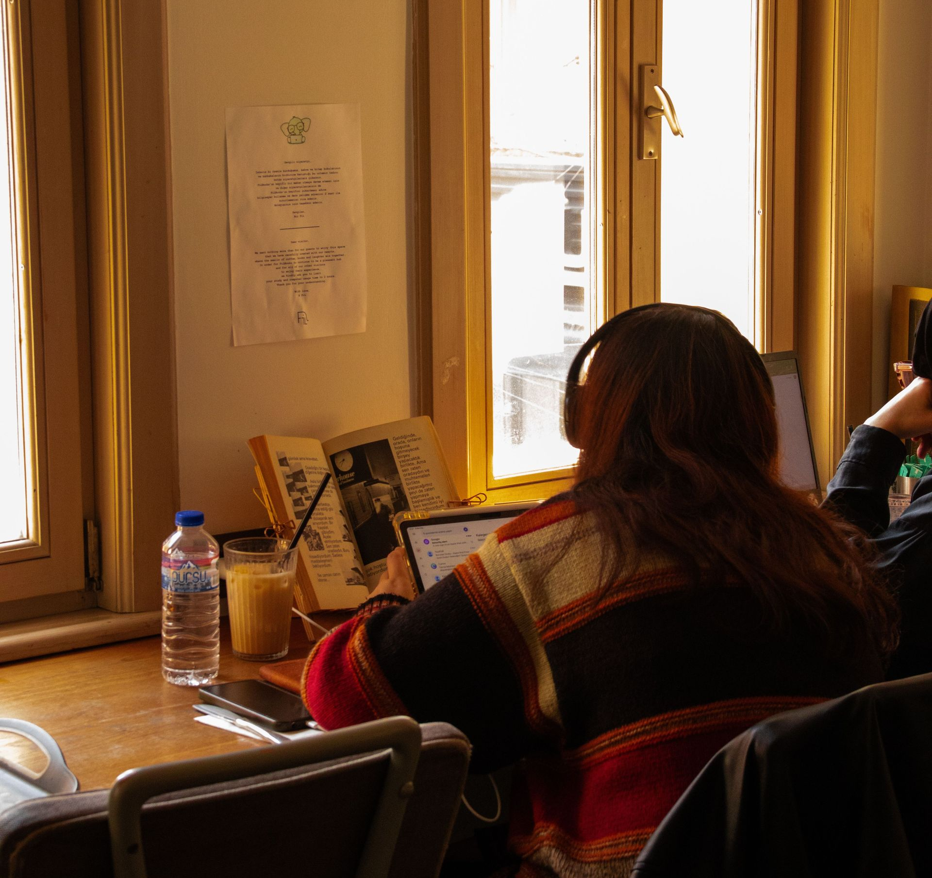 Woman using laptop near bright window