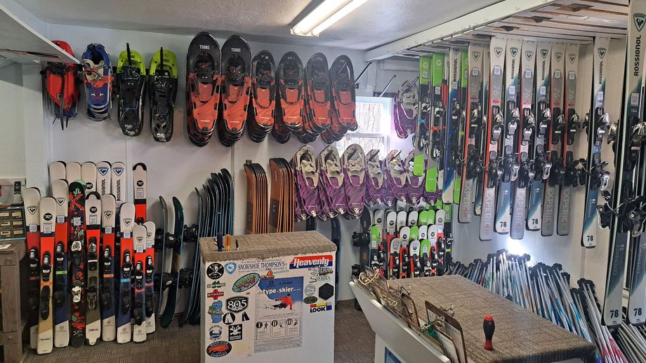 Ski shop wall with rows of skis and snowboards, plus display stands in the foreground