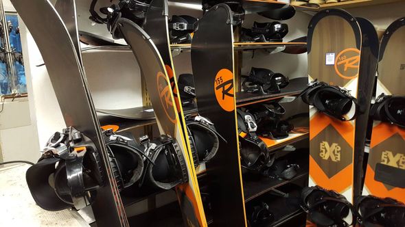 Row of black and orange snowboards displayed on shop racks indoors