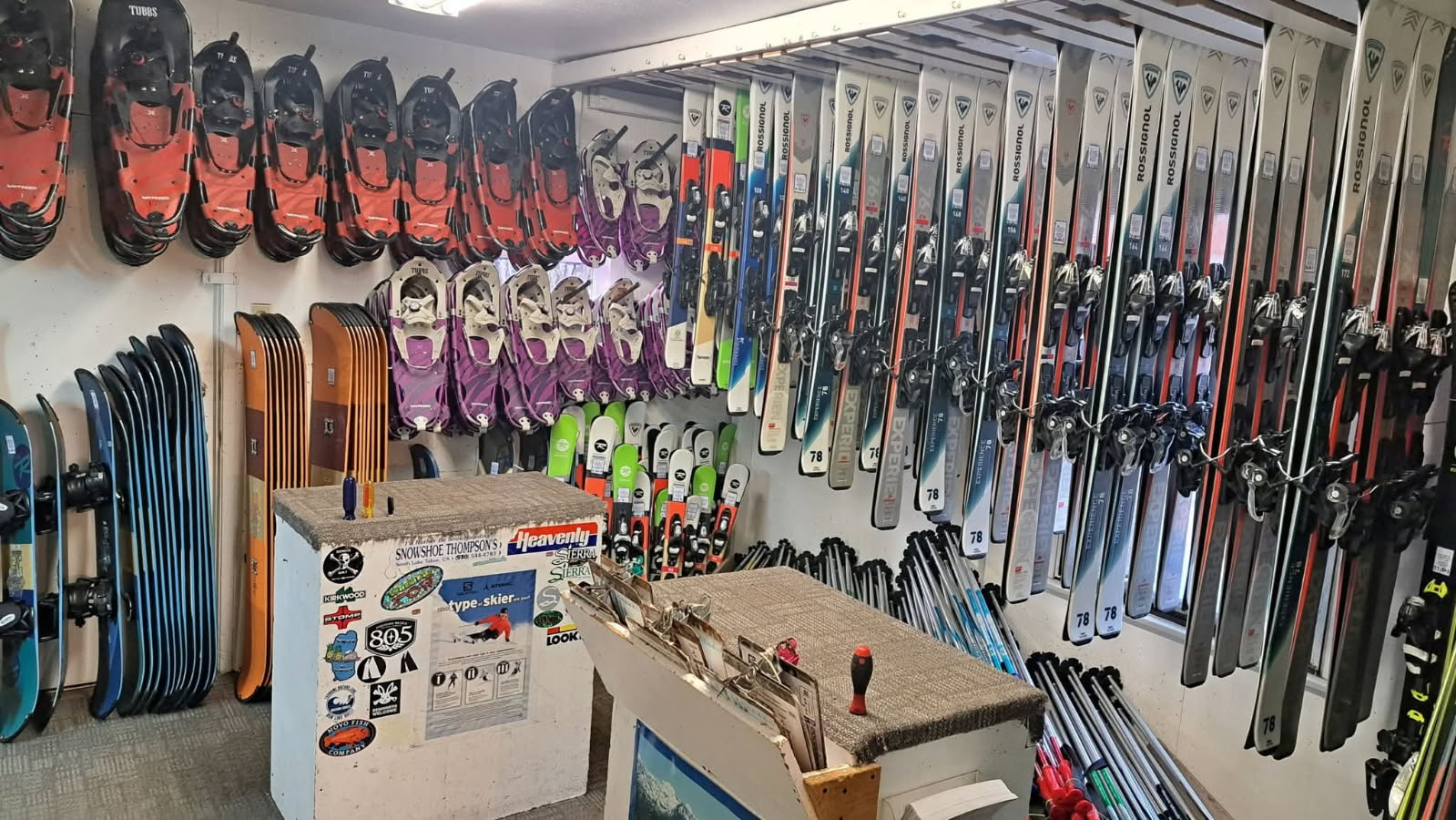 Ski shop wall lined with colorful skis and poles, with two display stands in the foreground.