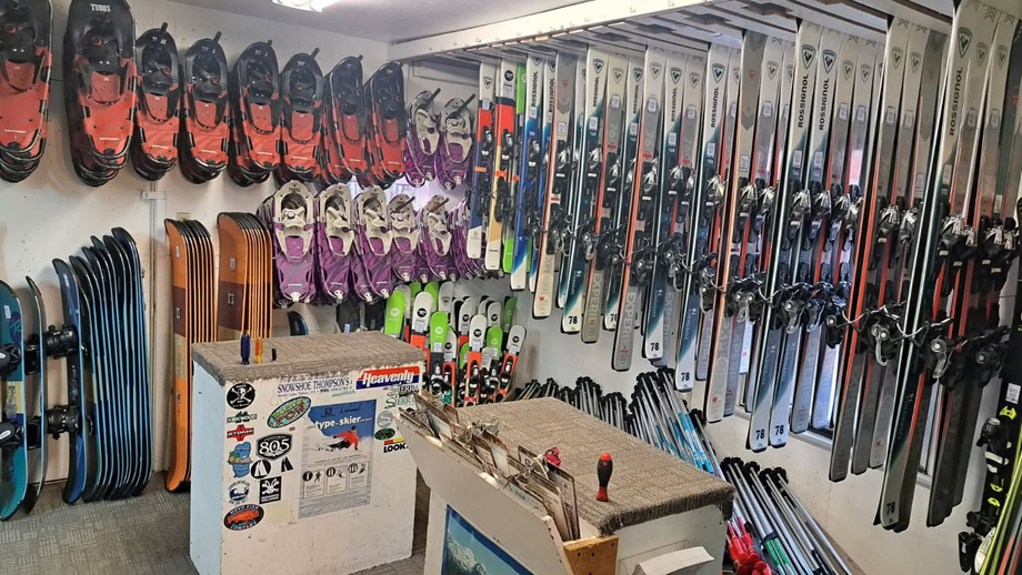 Indoor ski shop with rows of skis and snowboards on display and a counter in front