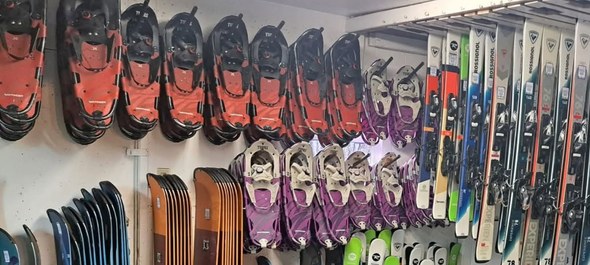 Row of colorful kayaks stacked side by side against a wall
