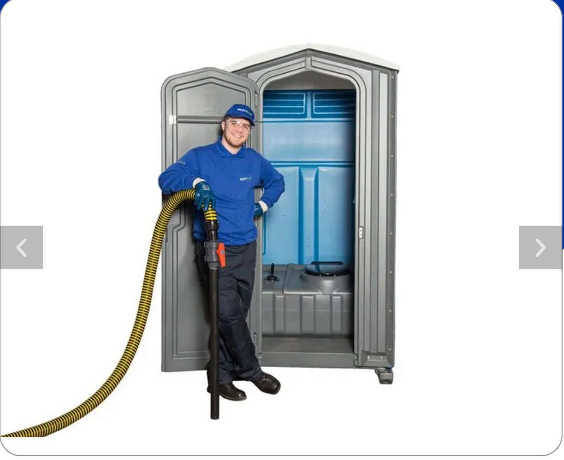 Person in blue uniform with hose stands beside a portable toilet with open door.