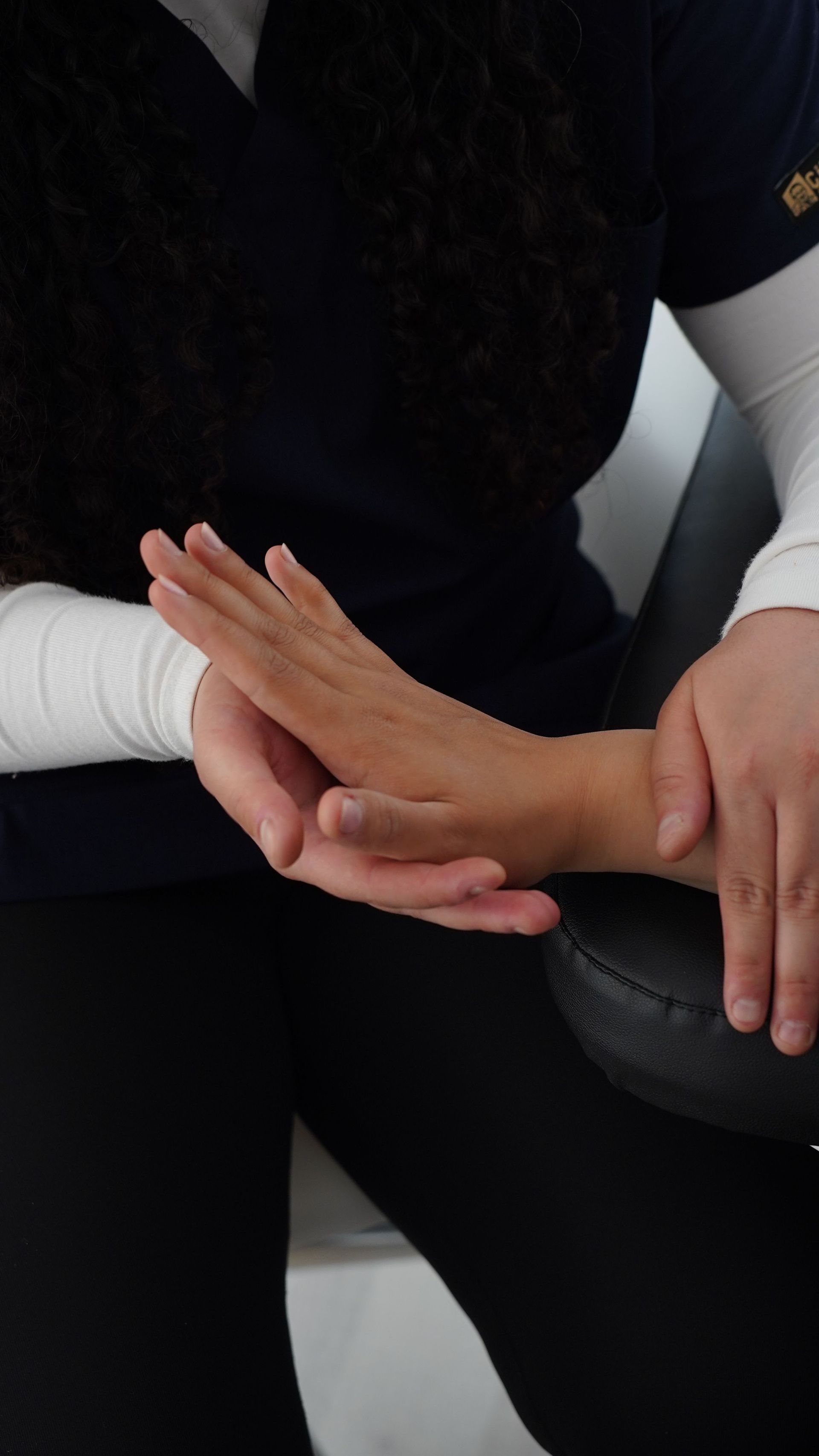 Dos personas tomadas de la mano, una de ellas con una manga blanca, sobre un fondo oscuro.