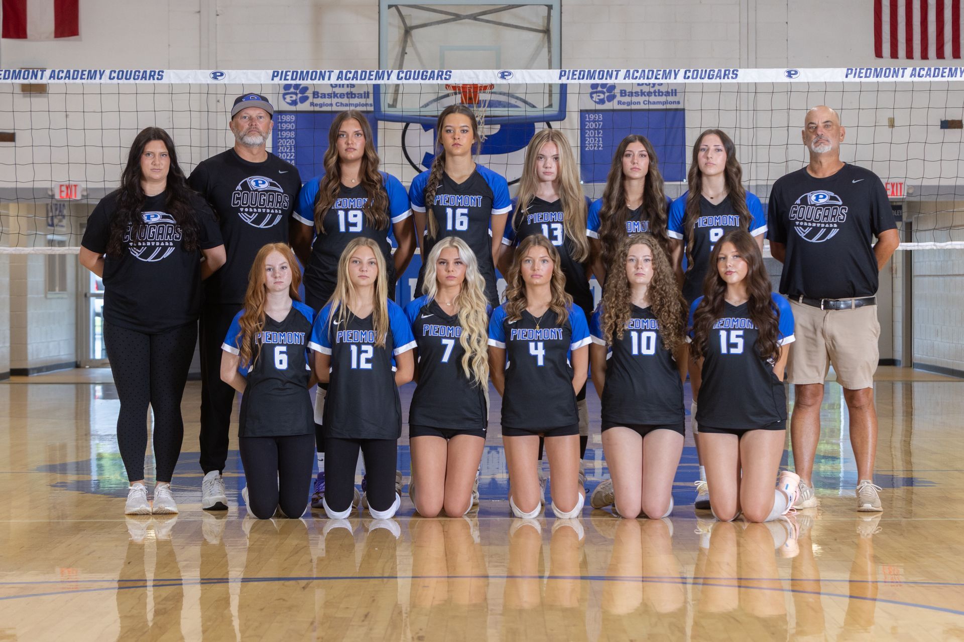 A group of young girls are posing for a volleyball team photo.
