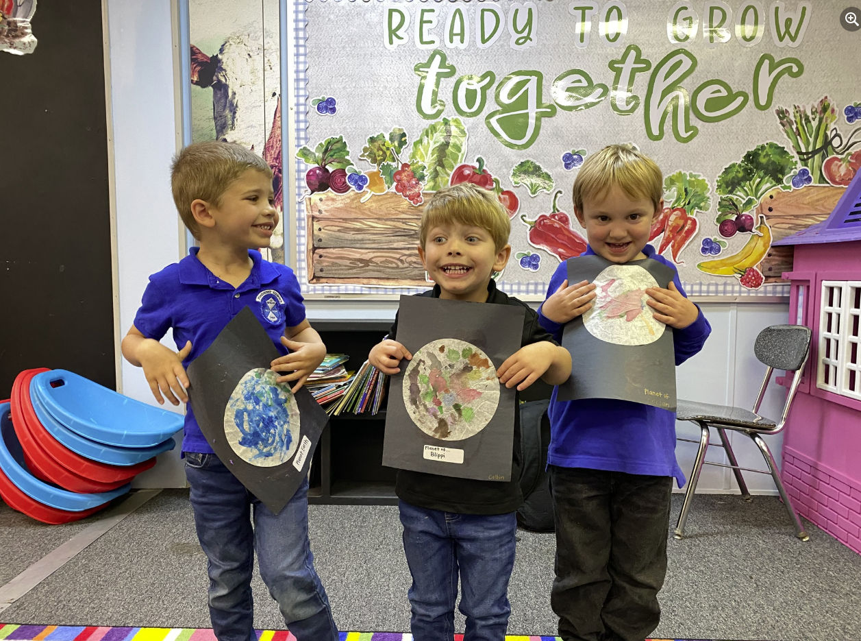Three young boys are standing in front of a sign that says ready to grow together.