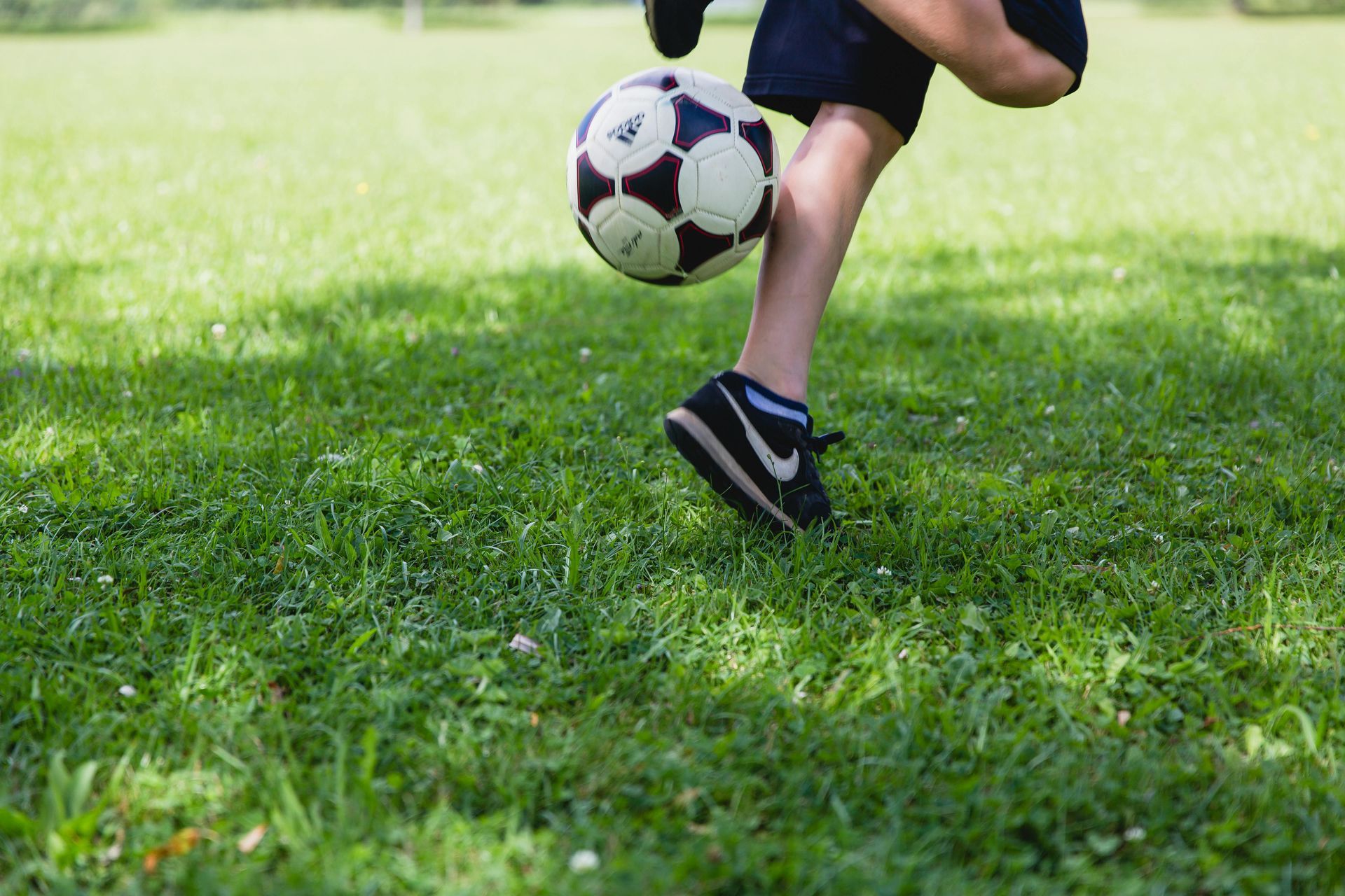 A person is kicking a soccer ball in the grass.