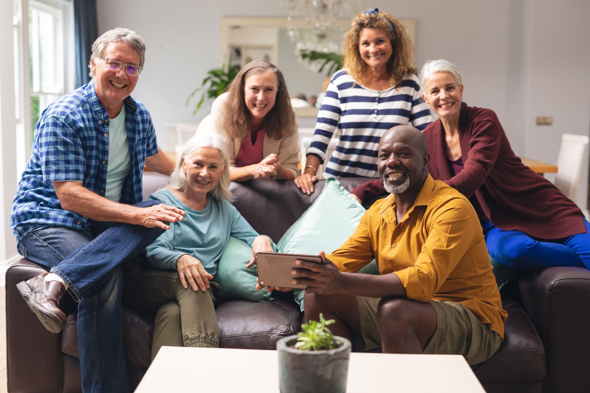 A group of people are sitting on a couch looking at a tablet.