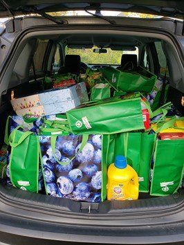 The back of a car is filled with shopping bags and groceries