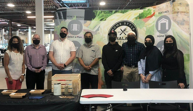A group of people wearing masks are standing around a table.