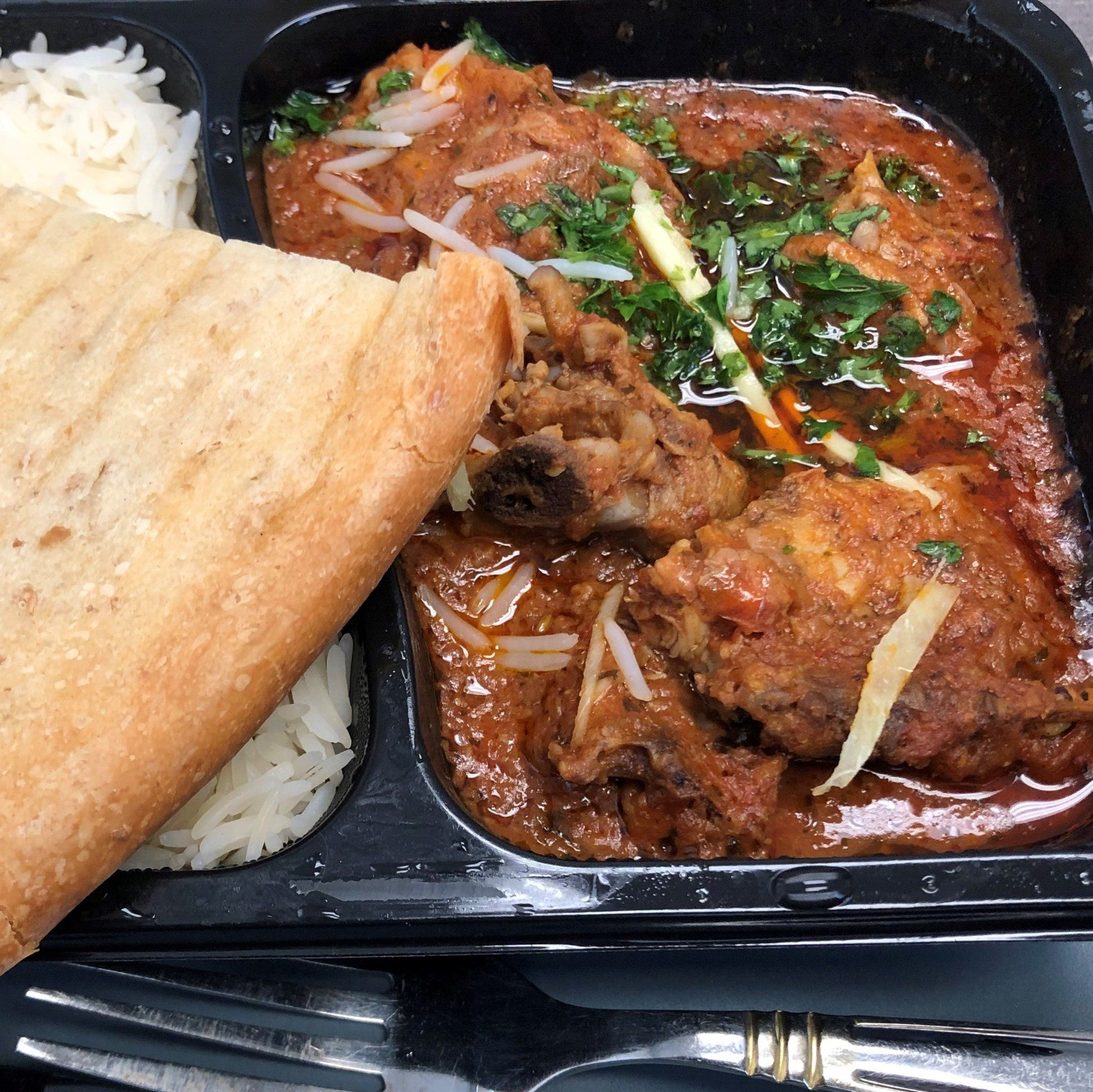 A tray of food with rice and a piece of bread