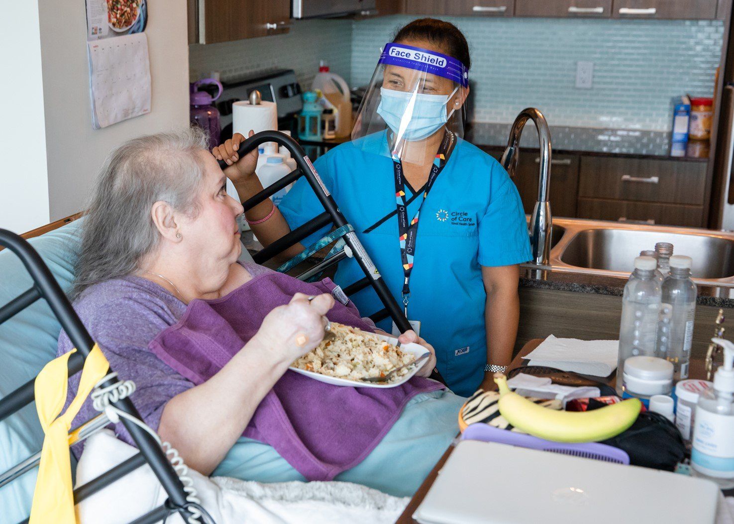 A nurse is feeding an elderly woman in a hospital bed.
