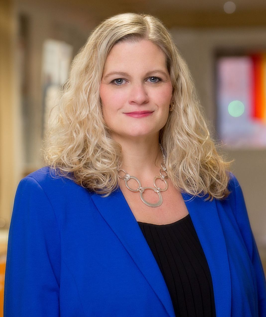A woman is wearing a blue jacket and a necklace.