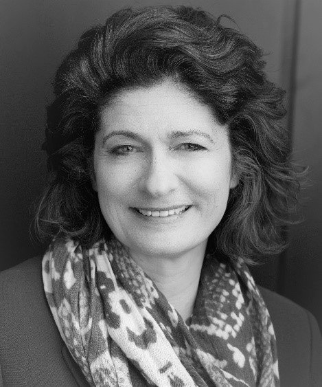 A black and white photo of a woman wearing a scarf and smiling.