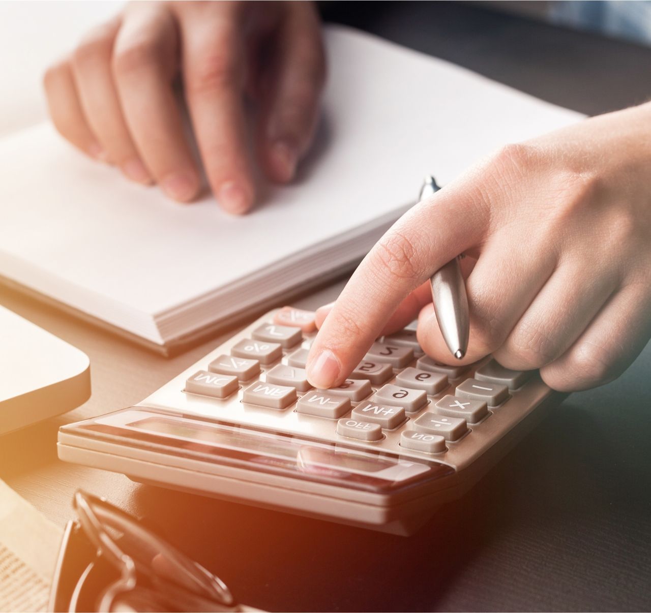 A person is using a calculator and writing on a piece of paper