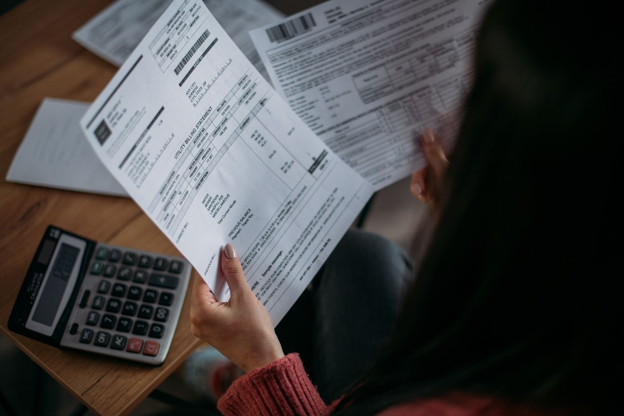 A woman is sitting at a table holding a piece of paper and a calculator.