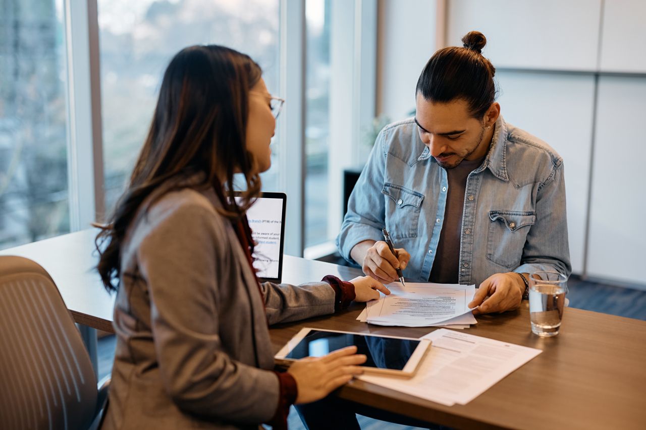 A man and a woman are sitting at a table looking at papers.