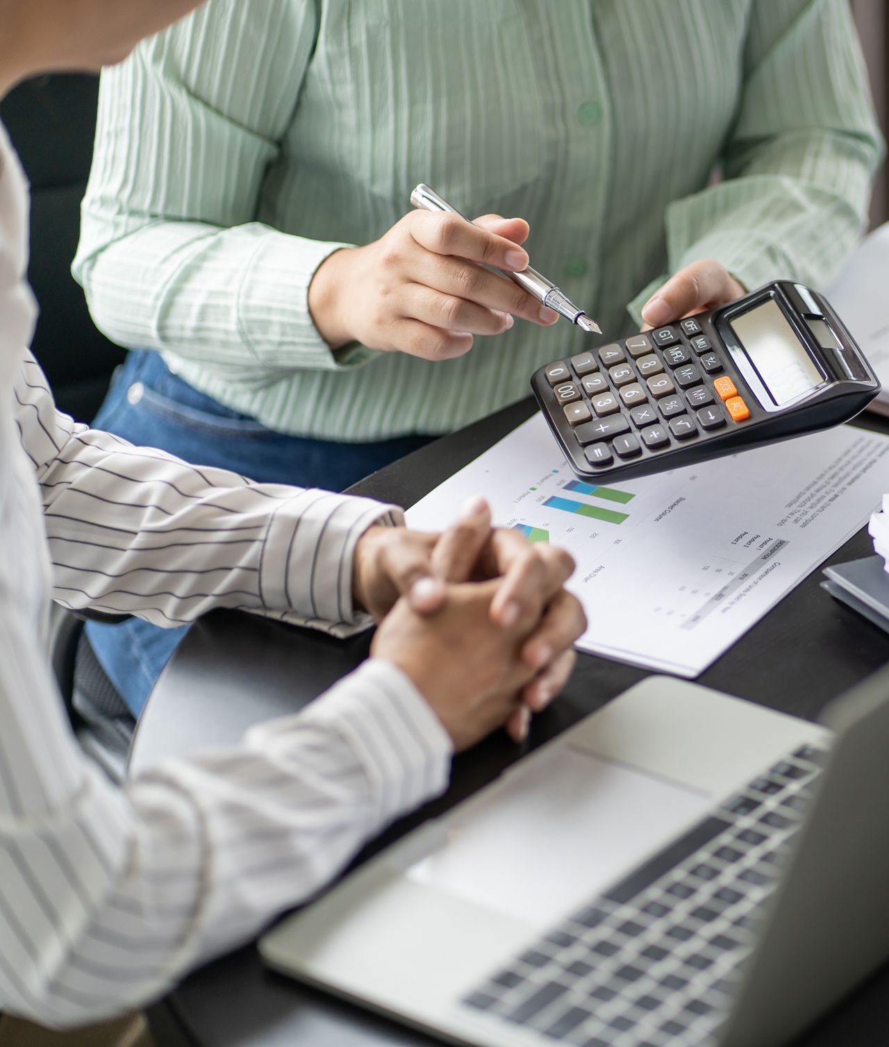 Two people are sitting at a table with a laptop and a calculator.