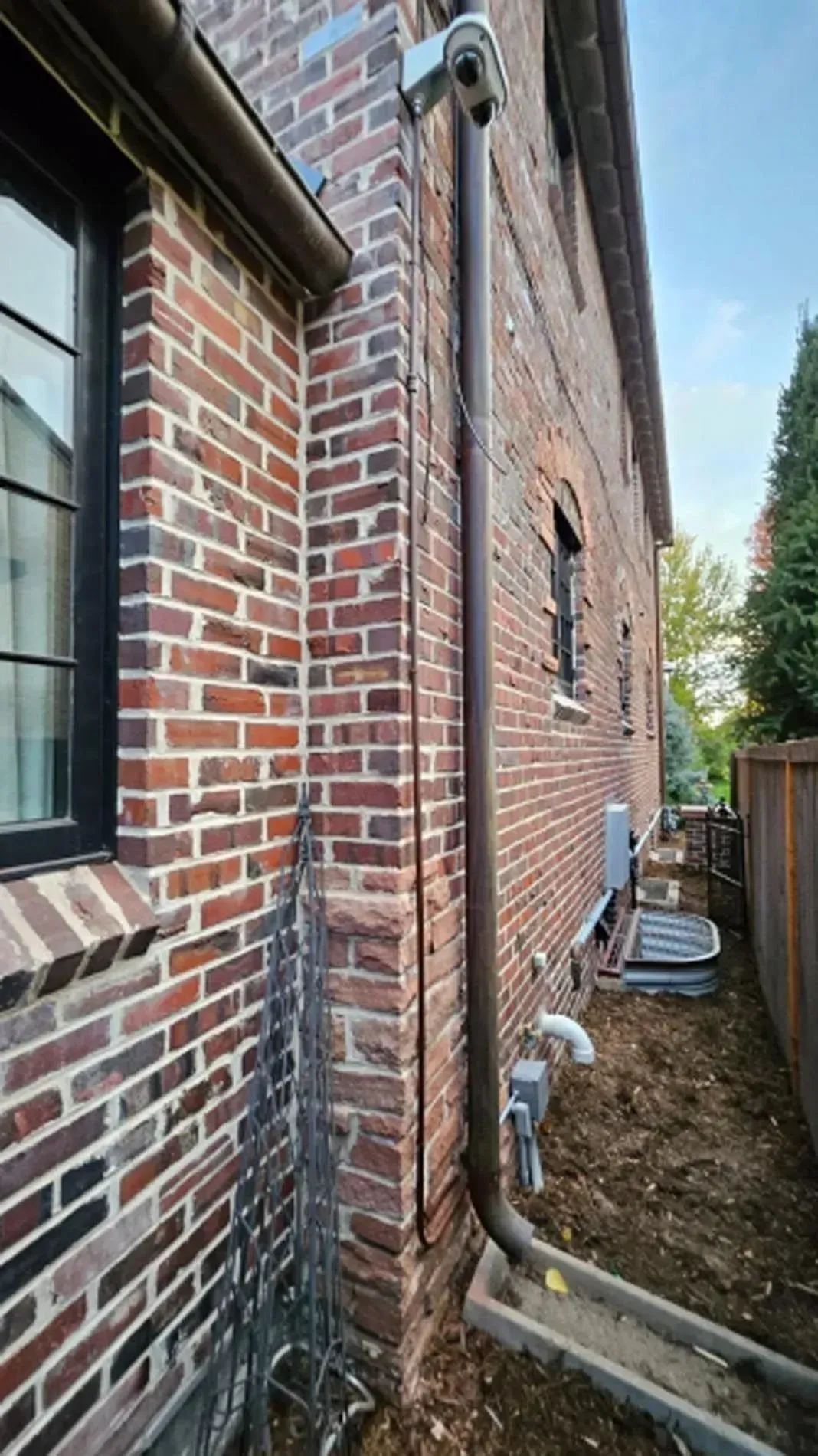 Brick townhouse with arched doorway, lush garden, and green lawn in front