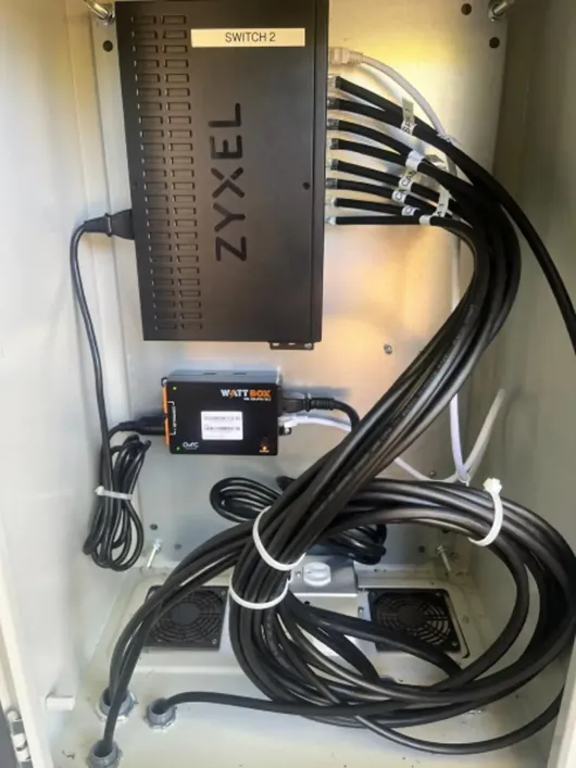 Zyxel network switch with bundled cables inside a wall-mounted cabinet