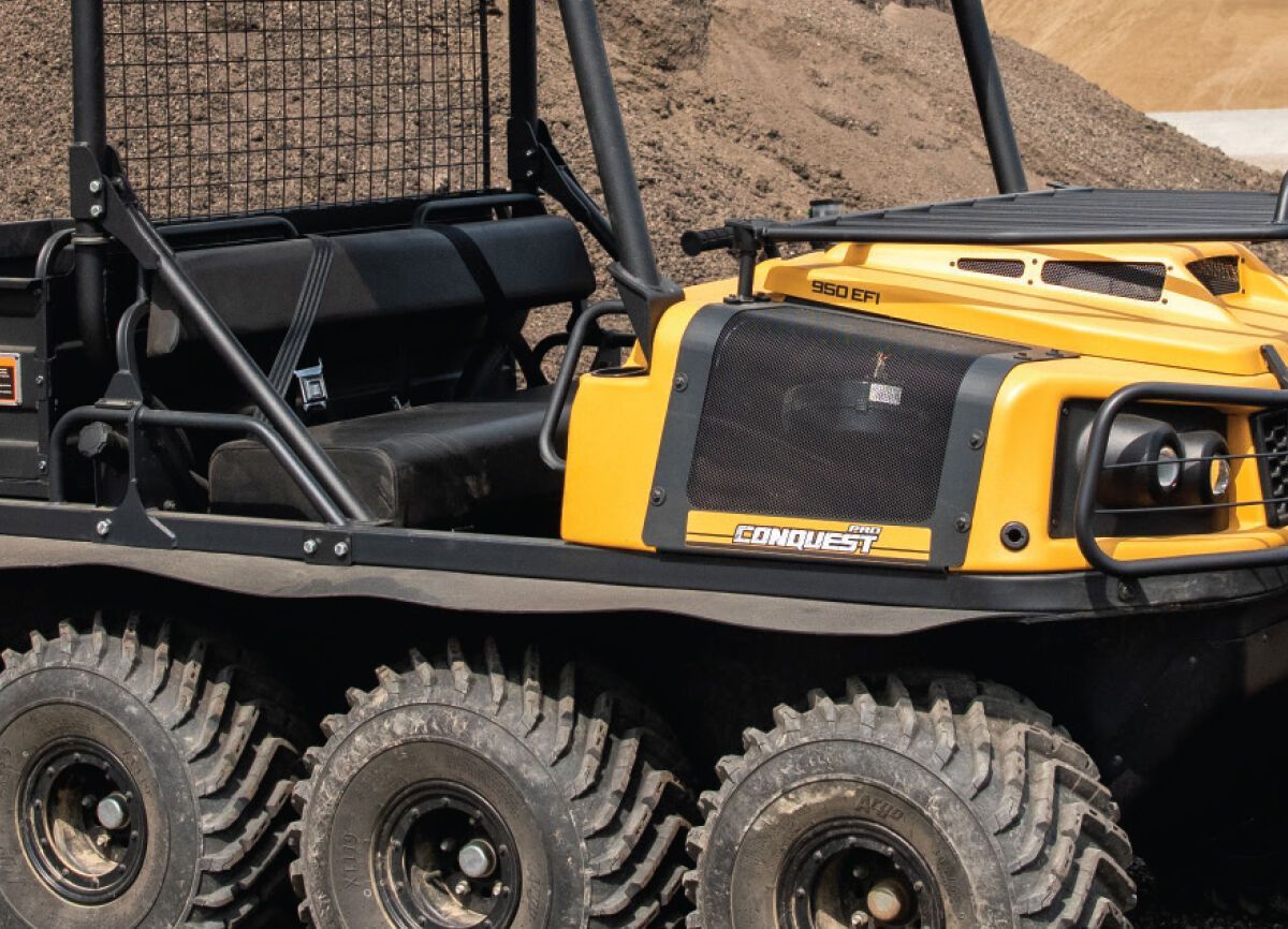 a yellow conquest XTV is parked in front of a pile of dirt
