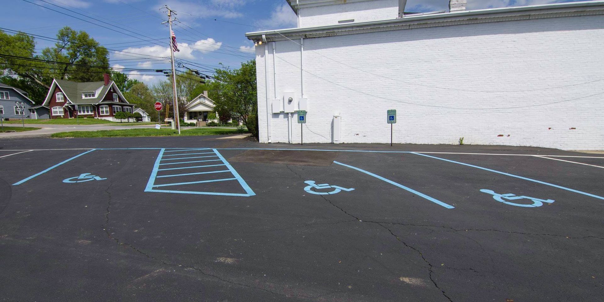 Empty accessible parking spaces outlined in blue beside a white building on a sunny day