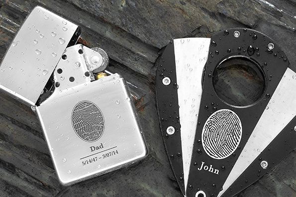 Three metal lighters on a wooden surface, each with a fingerprint design and the name John.