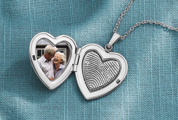 Heart-shaped silver locket open on blue fabric, showing a small photo inside.