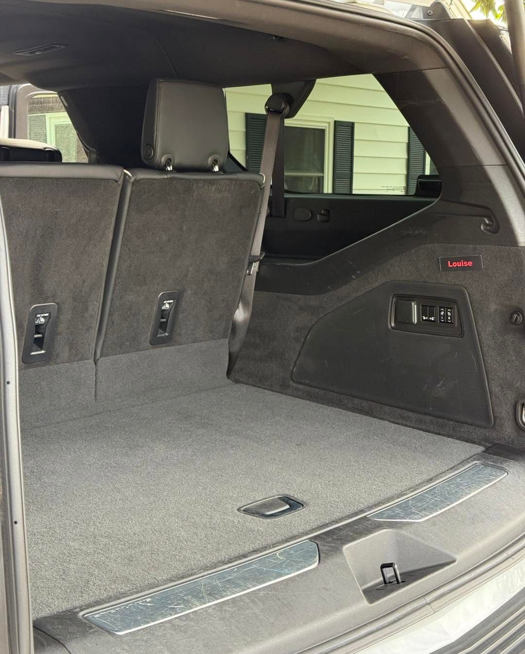 SUV cargo area with rear seats folded down, showing a carpeted trunk space and side storage panel.