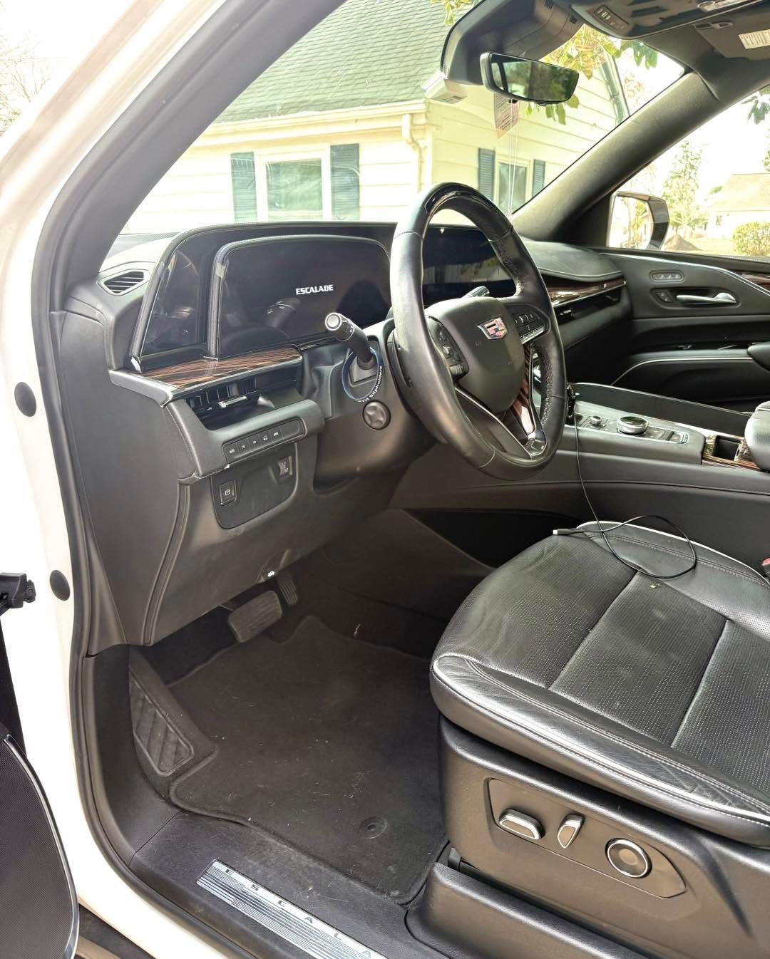Car interior showing the driver’s seat, steering wheel, dashboard, and open driver door