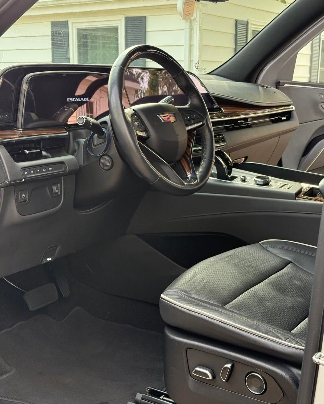 Luxurious car interior with leather seats, steering wheel, and dashboard visible from the open door