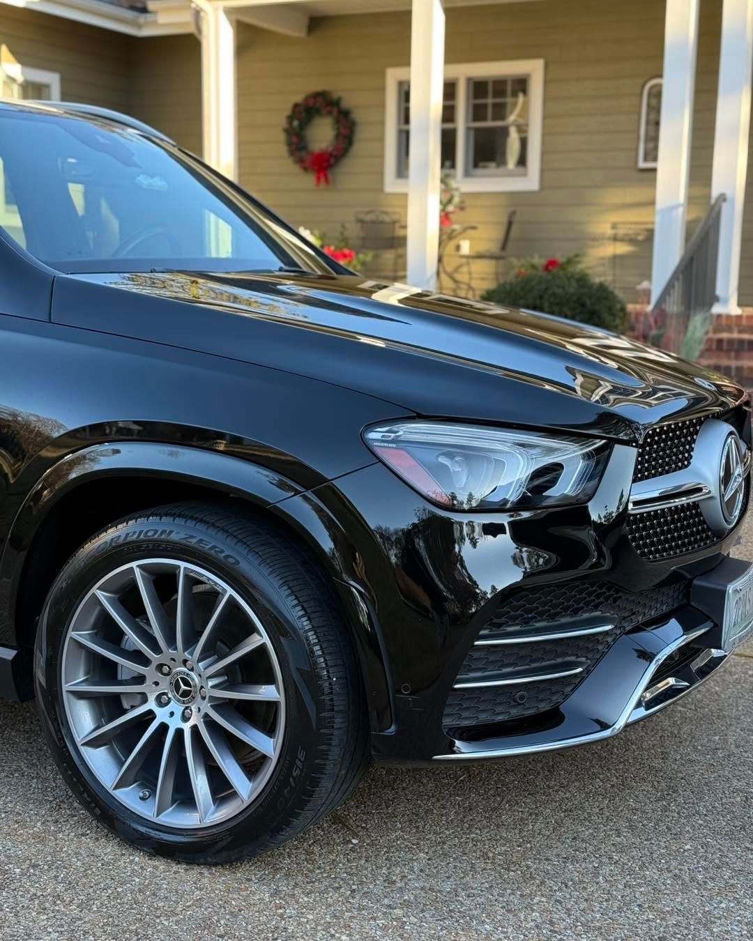 Black SUV parked outside a house with a wreath on the porch