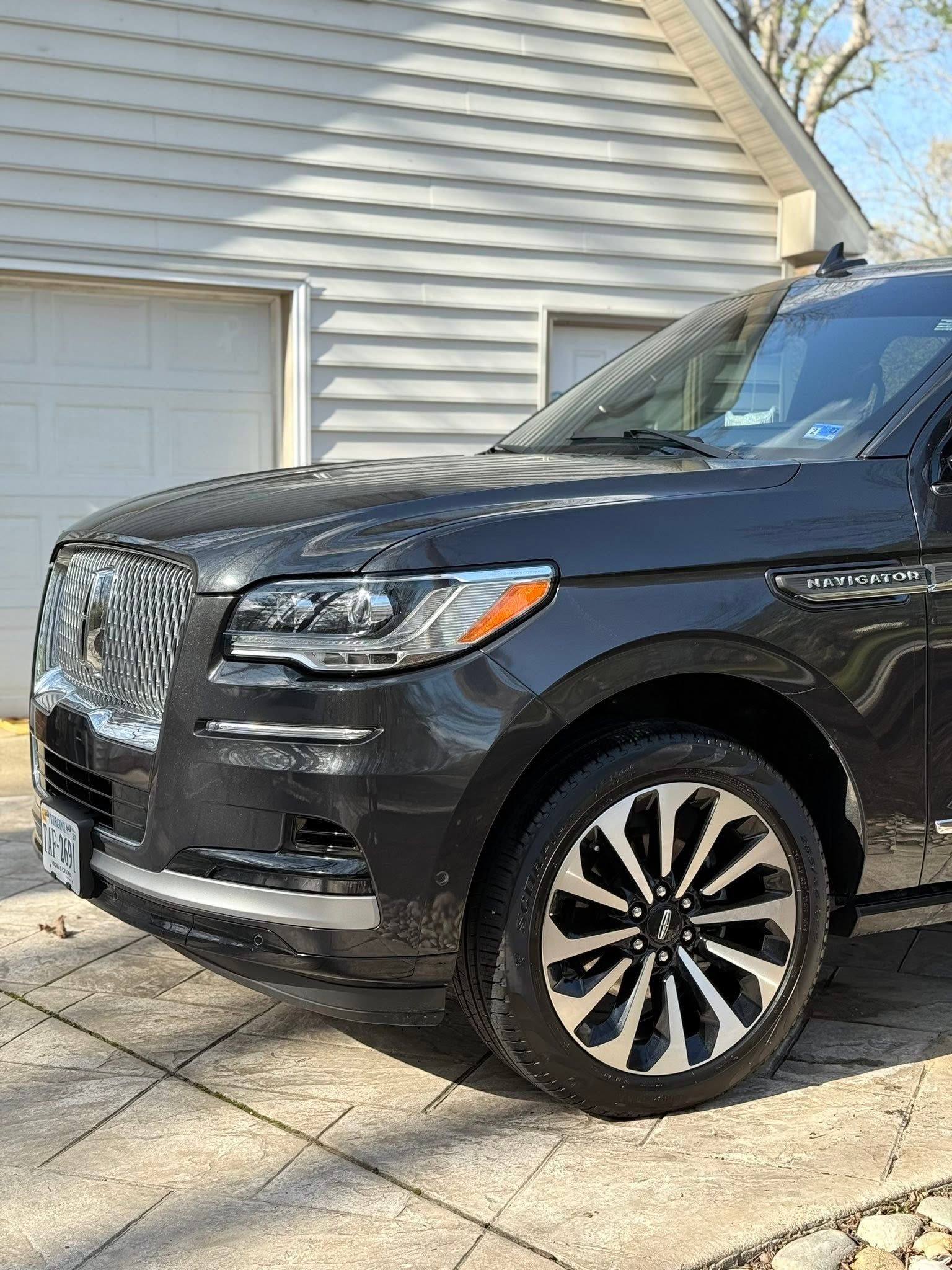 Black SUV parked in a driveway beside a white house and garage door