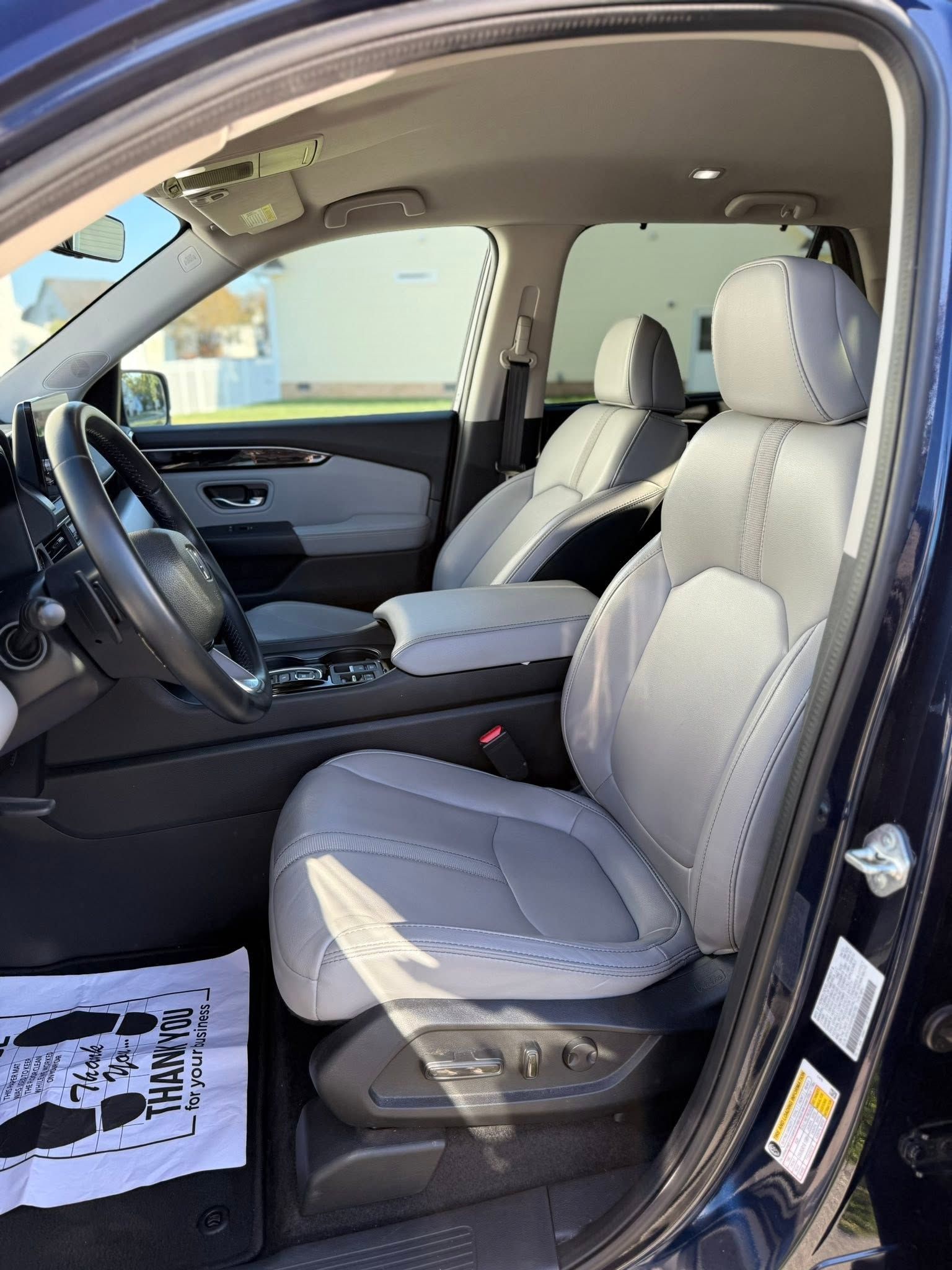 Open car door showing light gray front seats and black dashboard in a clean interior