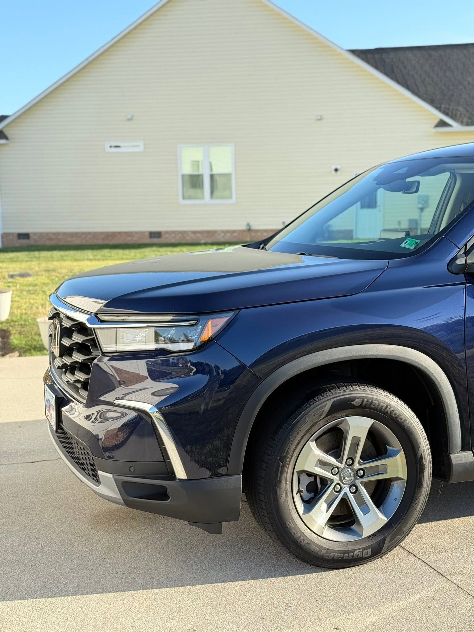 Dark blue SUV parked in front of a beige house with a garage.