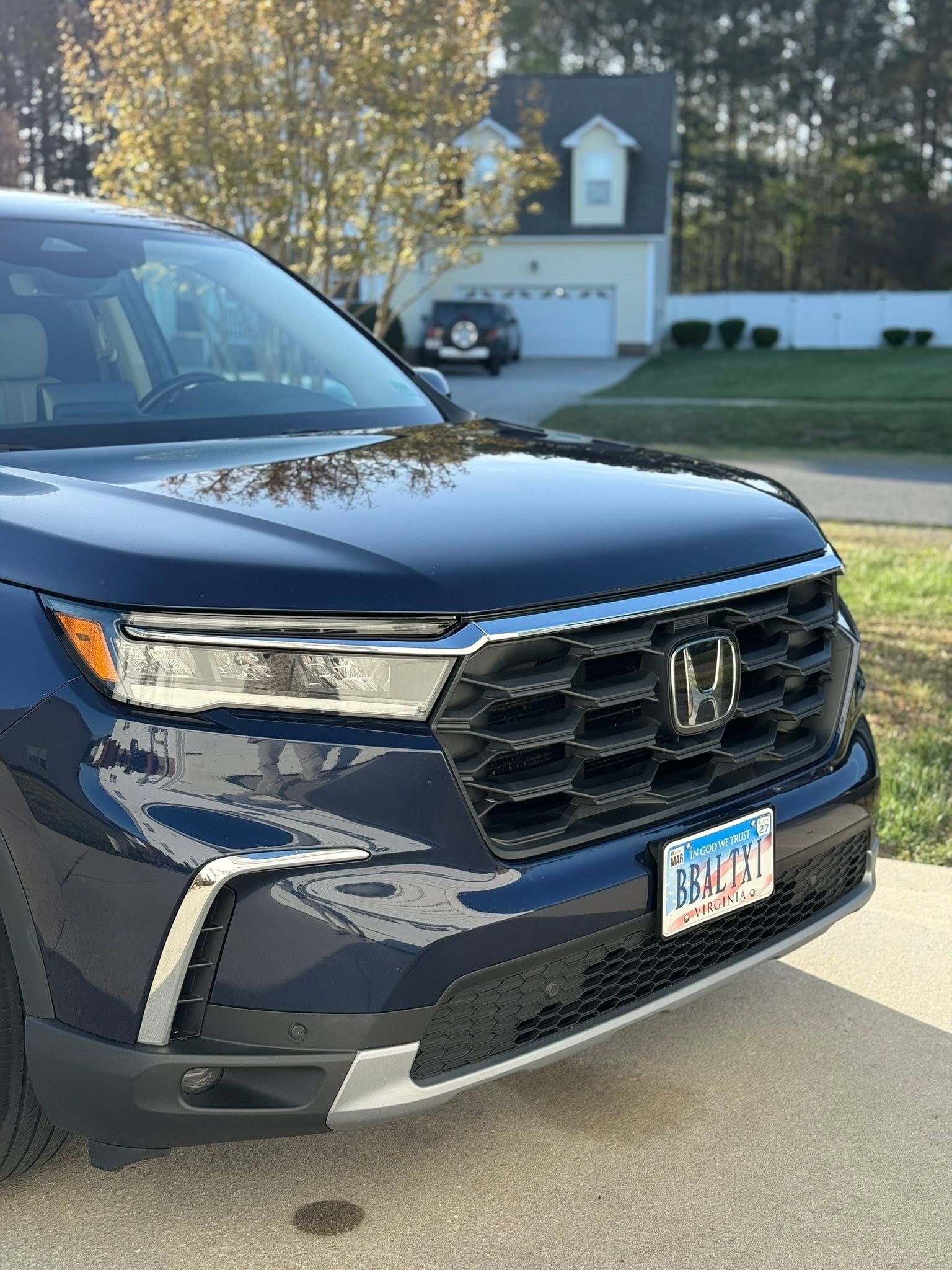Blue Honda SUV parked in a suburban driveway, front view with chrome grille and white garage in background