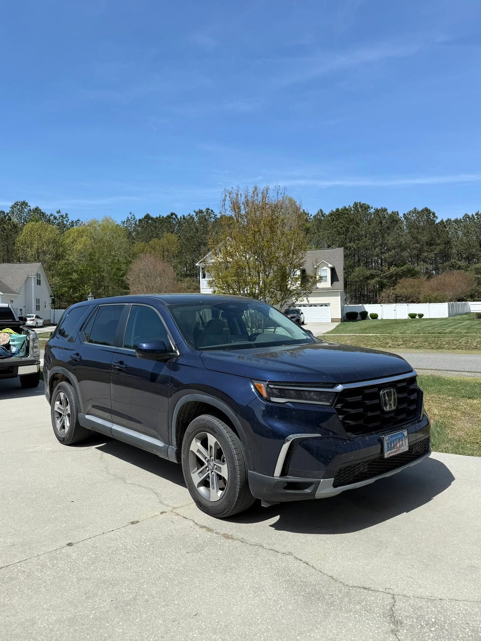 Dark blue SUV parked on a sunlit road with trees and buildings in the background