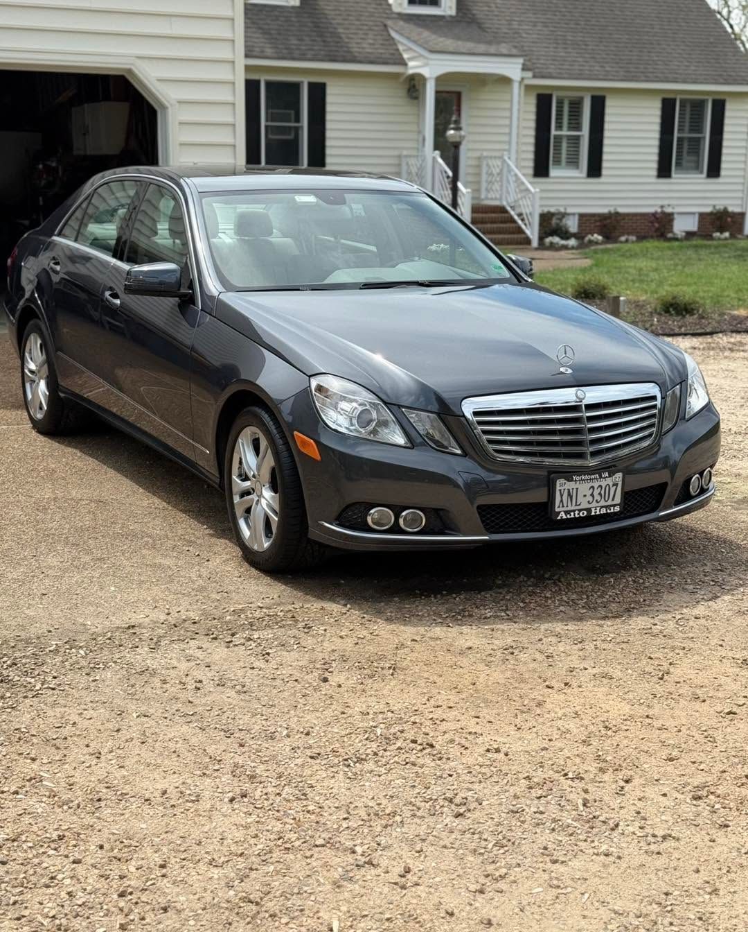 Dark gray sedan parked in a driveway in front of a suburban house