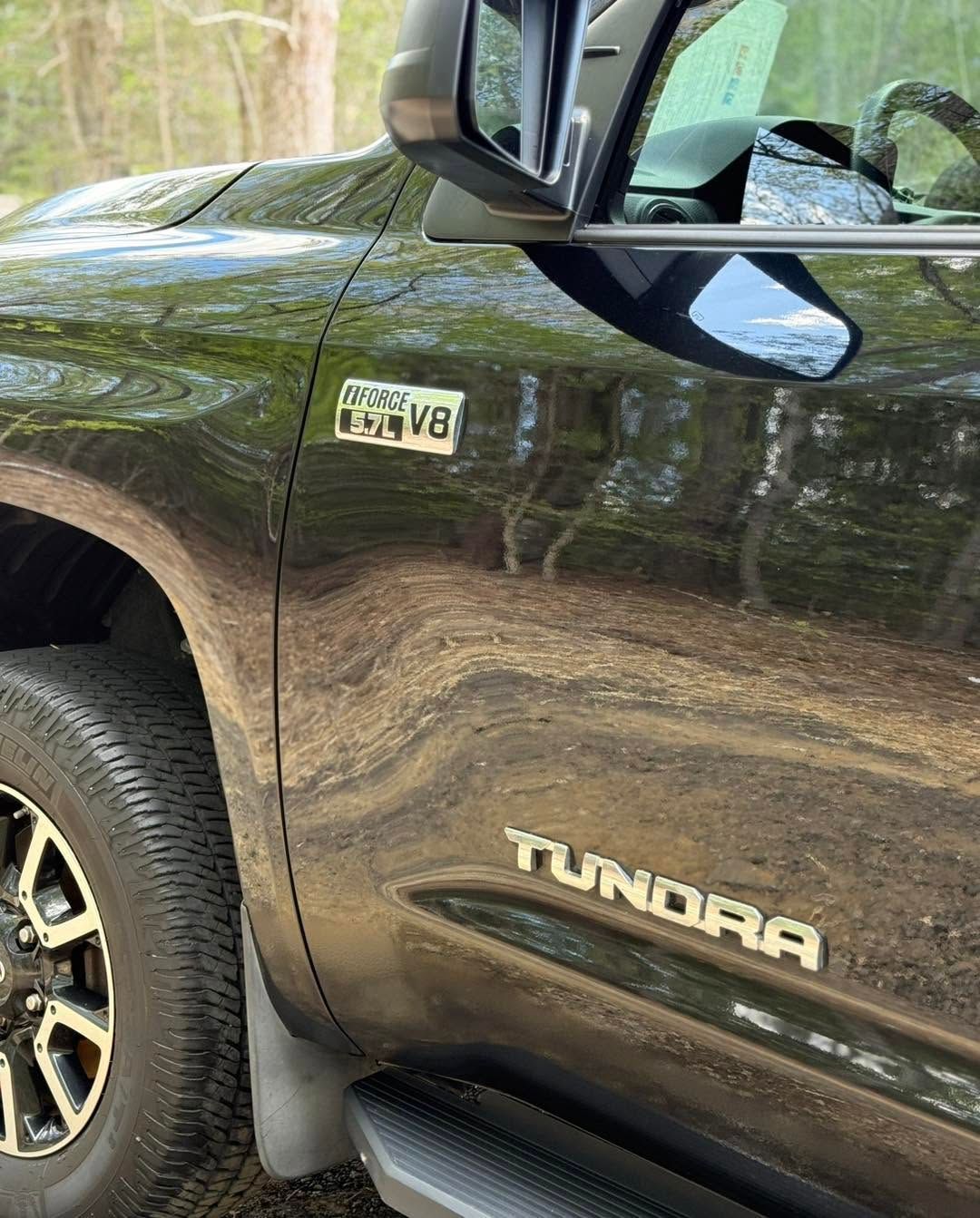 Close-up of a black Toyota Tundra truck with chrome trim and side mirror.